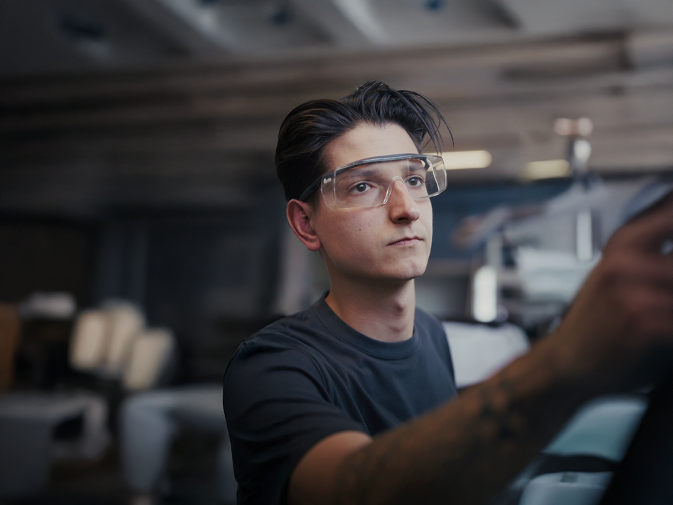Auszubildender mit Sicherheitsbrille in der Werkstatt. 